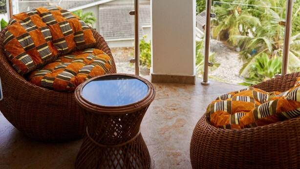 A balcony with wicker furniture and a view of a cityscape.