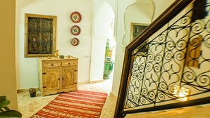 A staircase with ornate metal railings, a patterned carpet, a wooden cabinet, and decorative plates on the wall. - Riad Beni Sidel (Marrakech)