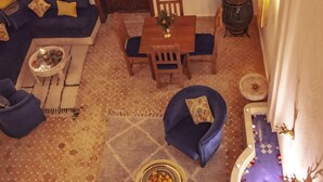 A cozy living area with a sofa set, a dining table with chairs, a coffee table, and a decorative bowl of fruit. - Riad Beni Sidel (Marrakech)