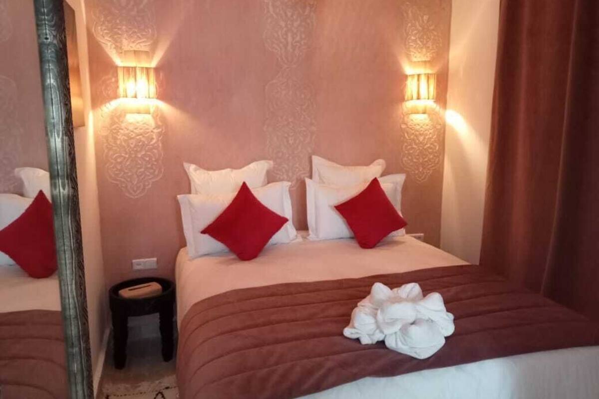 A hotel room with a bed, two bedside tables, and wall-mounted lamps.