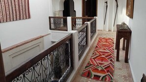 A corridor with a patterned carpet, a wooden railing, and a staircase. - Riad Beni Sidel (Marrakech)
