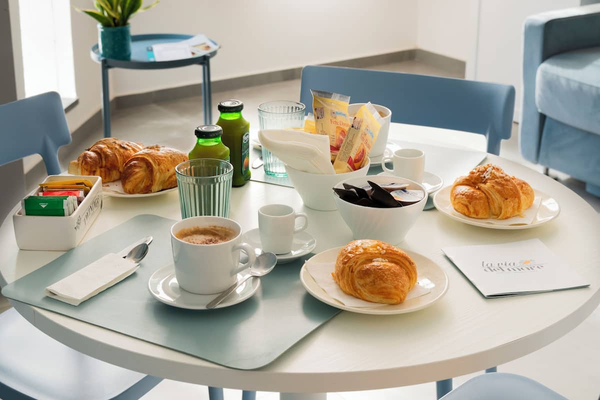 A dining table set with croissants, coffee cups, and a menu.