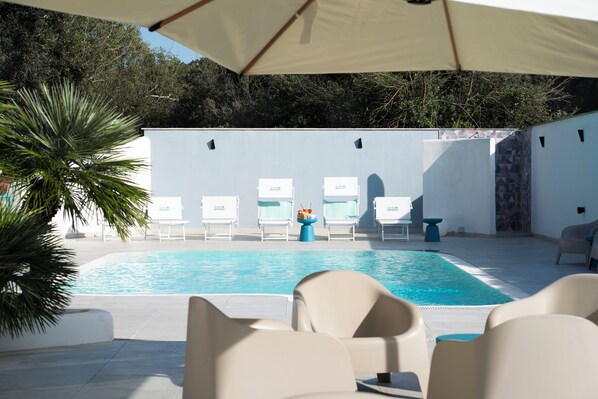 A swimming pool with lounge chairs and a palm tree. - La via del mare (Pozzuoli)