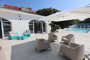 A modern outdoor seating area with lounge chairs and a pool. - La via del mare (Pozzuoli)