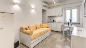 A compact living space with a sofa, kitchenette, and dining area. - Via Veneto Home (Roma)