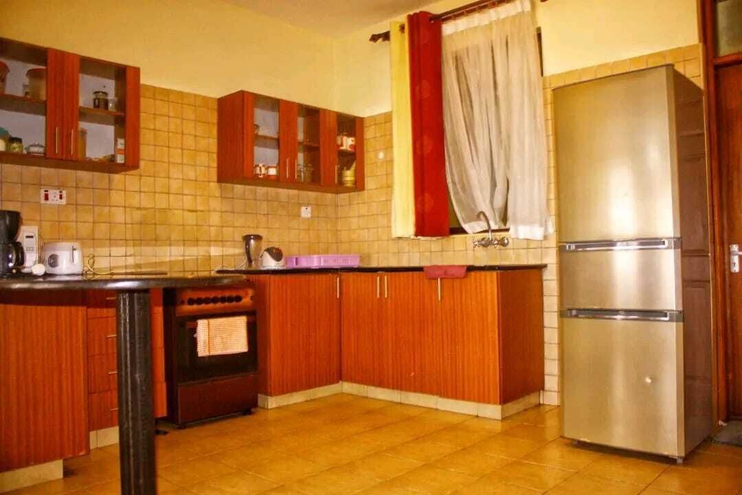 Eine Küche mit Holzausstattung, einem Edelstahlkühlschrank und einer gefliesten Spritzschutzwand.