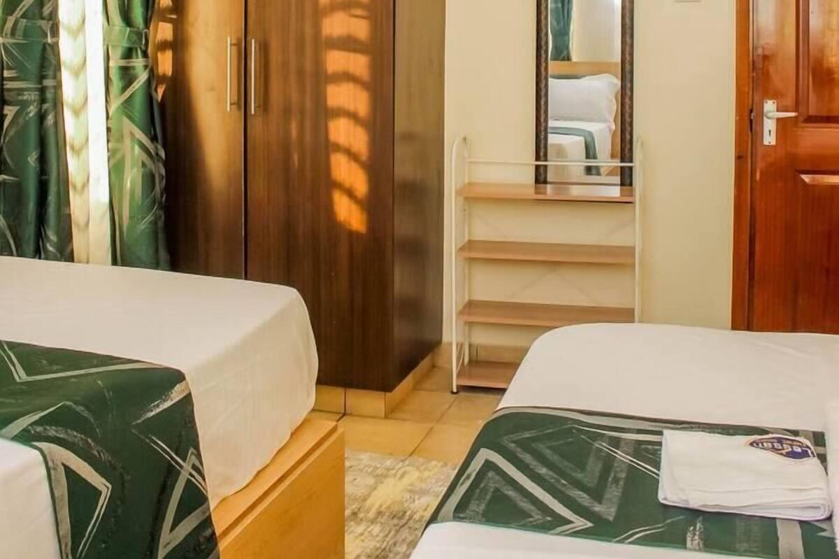 Une chambre d’hôtel avec deux lits, une armoire, un miroir et une fenêtre avec des rideaux.