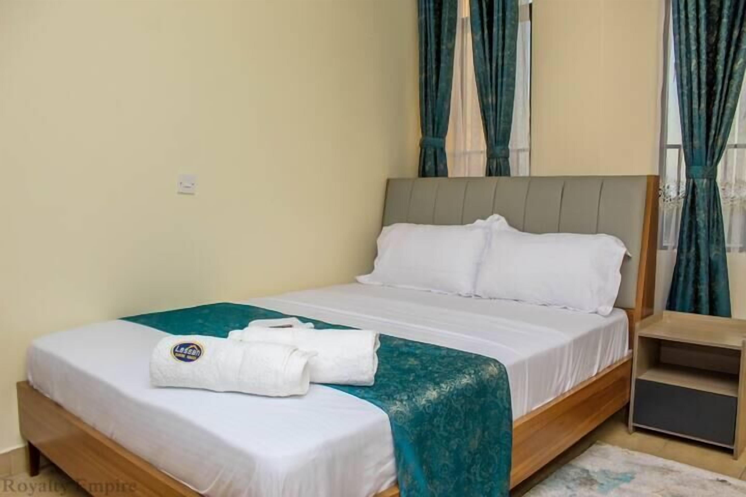 A hotel room with a bed, a nightstand, and a window with curtains.