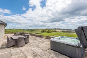 An outdoor patio with wicker furniture and a hot tub. - 5 Bed Villa - Sleeps 10 - Hot Tub - Country Views (Ardmore)