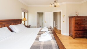 A hotel room with a large bed, a wooden dresser, and a bathroom visible through an open door. - 5 Bed Villa - Sleeps 10 - Hot Tub - Country Views (Ardmore)