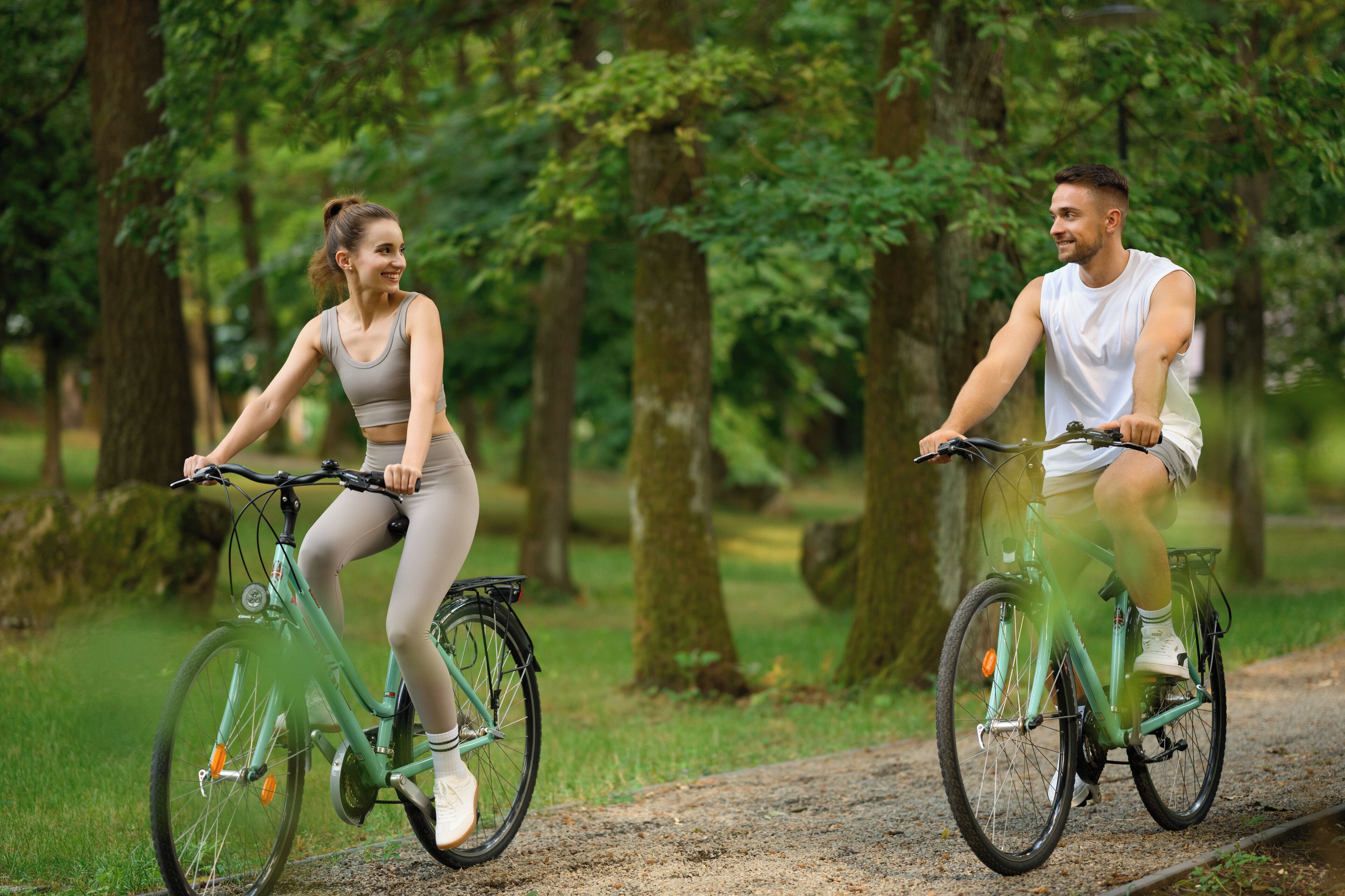 Two people riding bicycles on a path in a park.