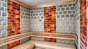 A sauna with wooden benches and a brick wall.