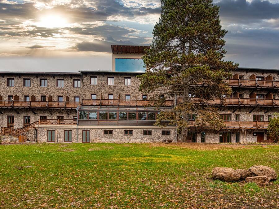 Un edificio de piedra grande con varias ventanas y una sección central de vidrio.