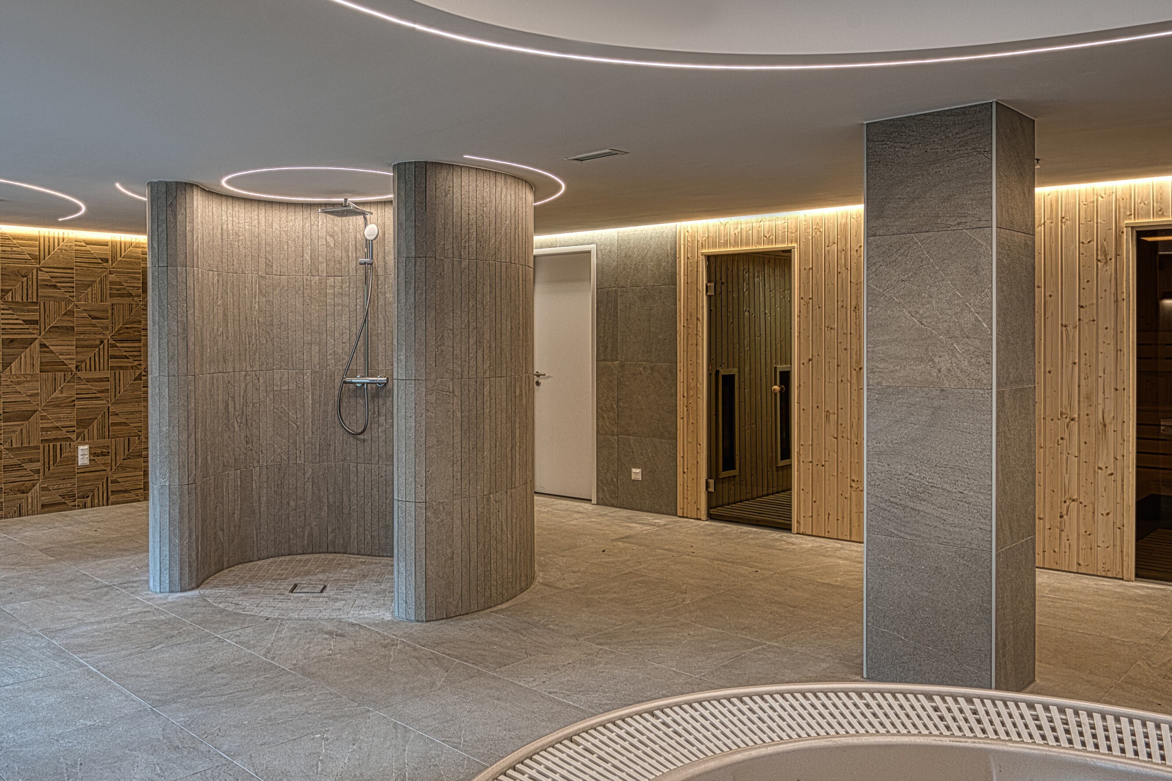 A modern bathroom with a shower, wooden panel walls, and a stone column.