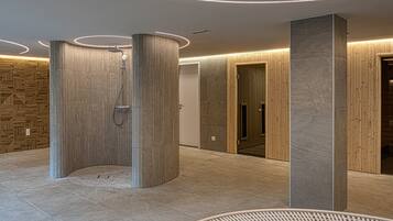 A modern bathroom with a shower, wooden panel walls, and a stone column.