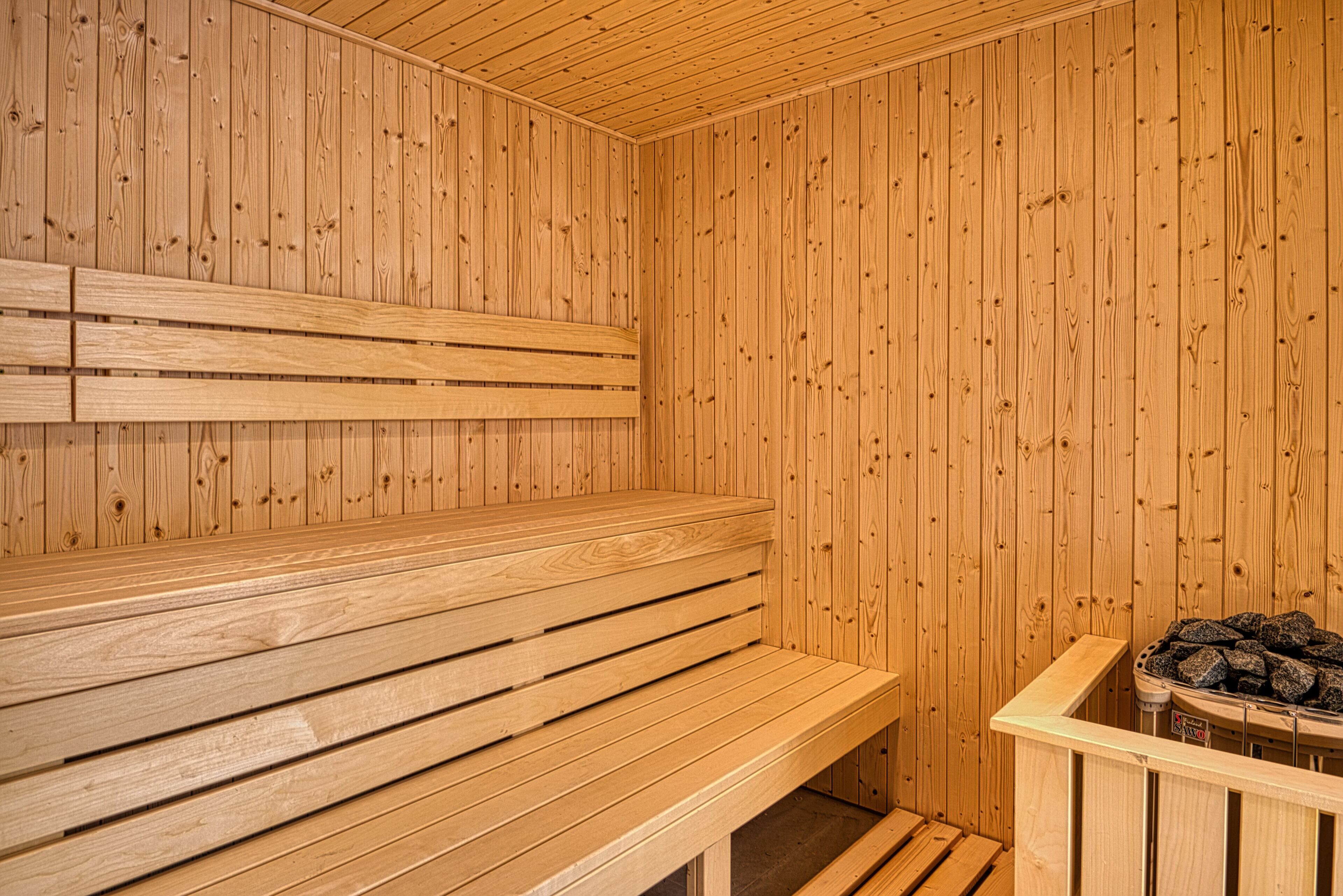 A wooden sauna with benches and a stone heater.