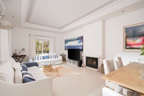 Relax in this stylish living room with a large flat-screen TV, comfortable sofa, and a cozy fireplace.