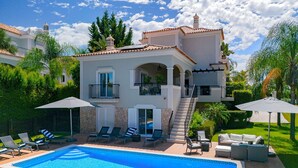 A two-story house with a swimming pool, outdoor seating, and a well-maintained garden.