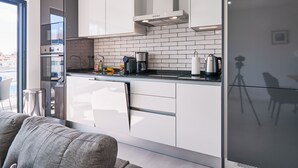 A modern kitchen with white cabinets, a black countertop, and a stainless steel refrigerator. - Terrace Daniel (Portimao)