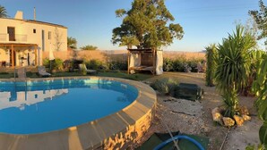 Une maison à deux étages avec une piscine, un espace salon extérieur et un jardin.