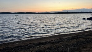 Une plage où l’eau est calme et le ciel dégagé au coucher du soleil.