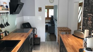 Une cuisine moderne dotée d’une hotte noire, de plans de travail en bois, d’un four encastré et d’une machine à café.