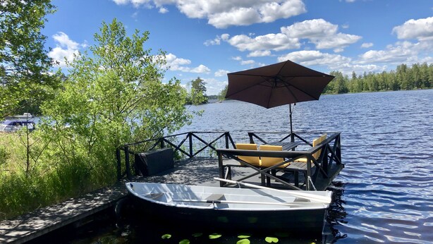 Un quai avec un bateau, une table avec des chaises et un parasol.