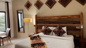 A hotel room with a large bed, a wooden headboard, a bedside table with a lamp, and a view of the outdoors through a window. - African Hill Hotel & Resort (Ho)