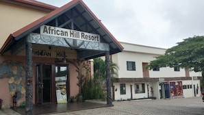 The entrance to African Hill Resort with a covered entrance, a signboard, and a paved courtyard. - African Hill Hotel & Resort (Ho)