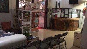 A hotel reception area with a reception desk, chairs, a glass display case, and a sign for African Hill Hotel & Resort. - African Hill Hotel & Resort (Ho)