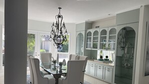 Una cucina moderna con mobili bianchi, schienale in vetro e lampadario.