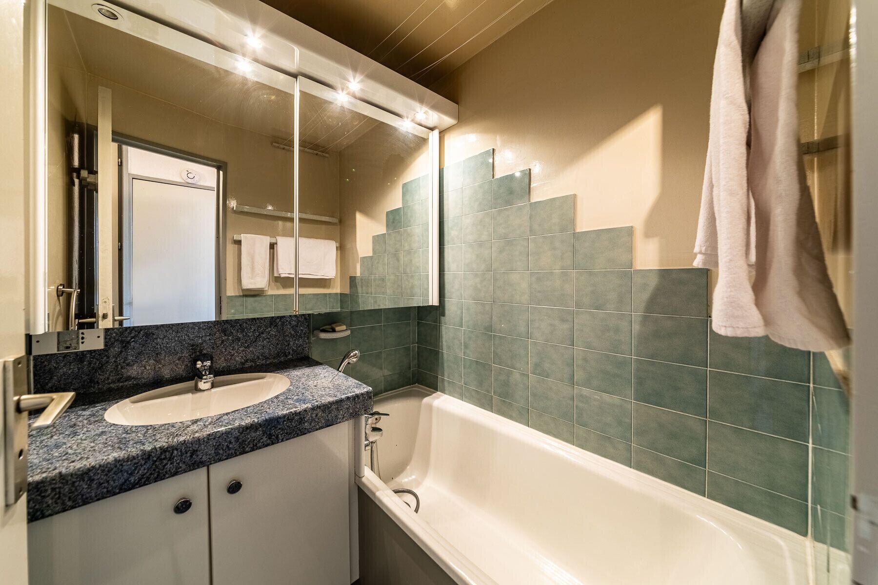 Un baño con tocador doble, bañera y espejo con iluminación superior.