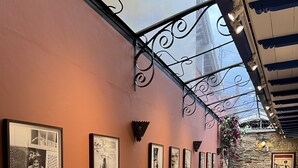 Un couloir orné de photographies encadrées accrochées au mur, un mur en pierre et un sol carrelé.