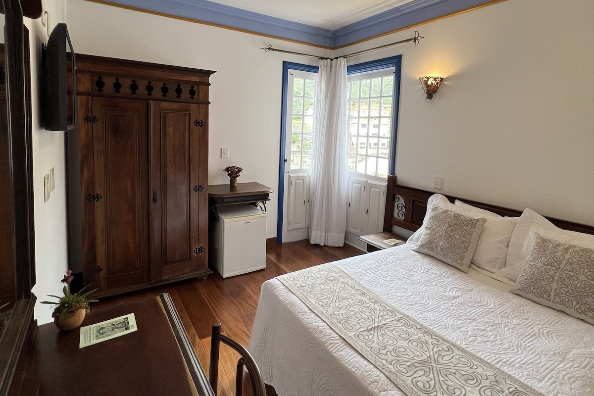 Un dormitorio con una cama grande, un aparador de madera, un escritorio y una ventana con cortinas.
