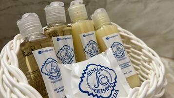 Cestino con diverse bottiglie di shampoo e balsamo, con etichette che indicano che provengono da 'Sinha Olimpia'.
