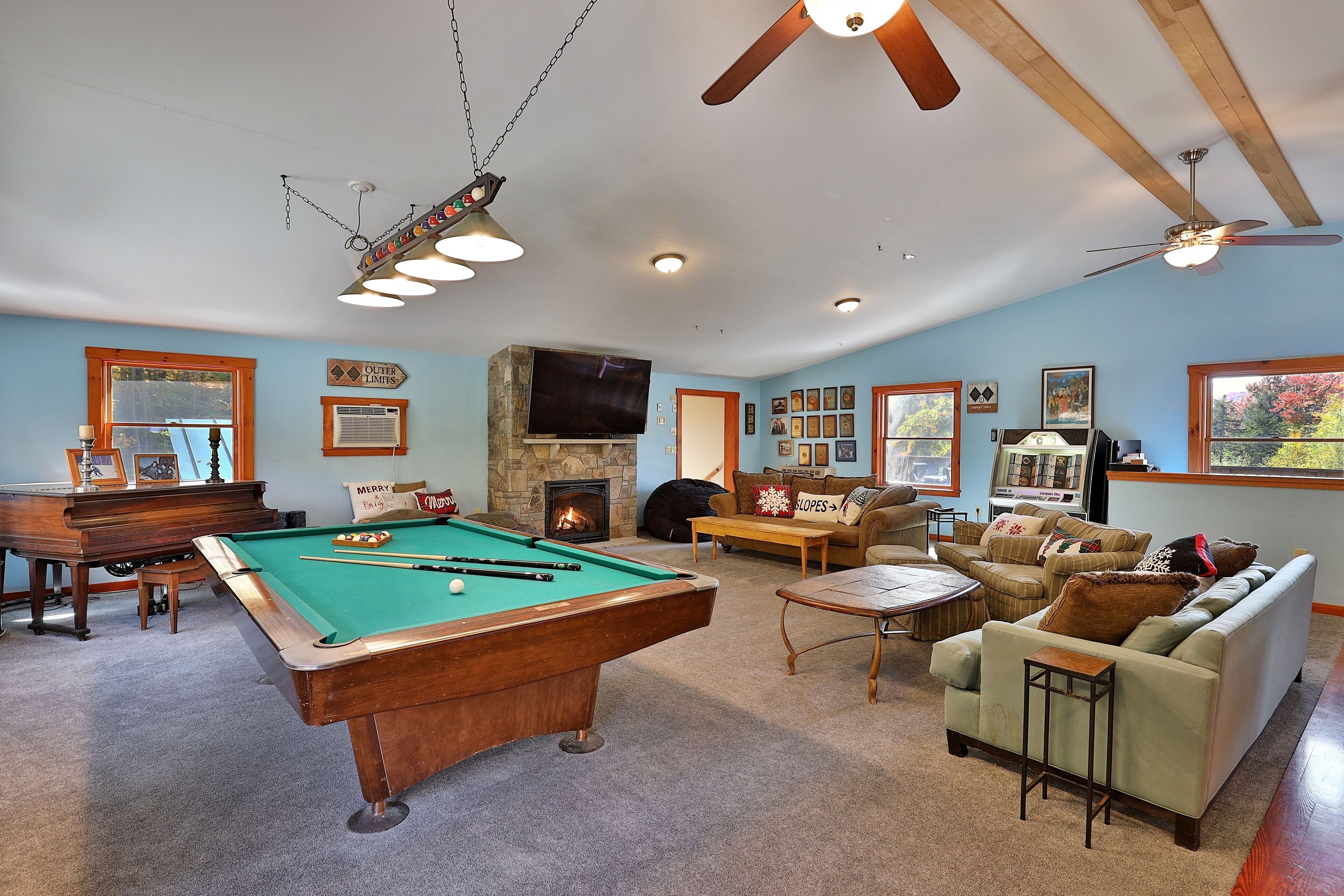 A spacious living room with a pool table, a fireplace, a sofa, and a ceiling fan.