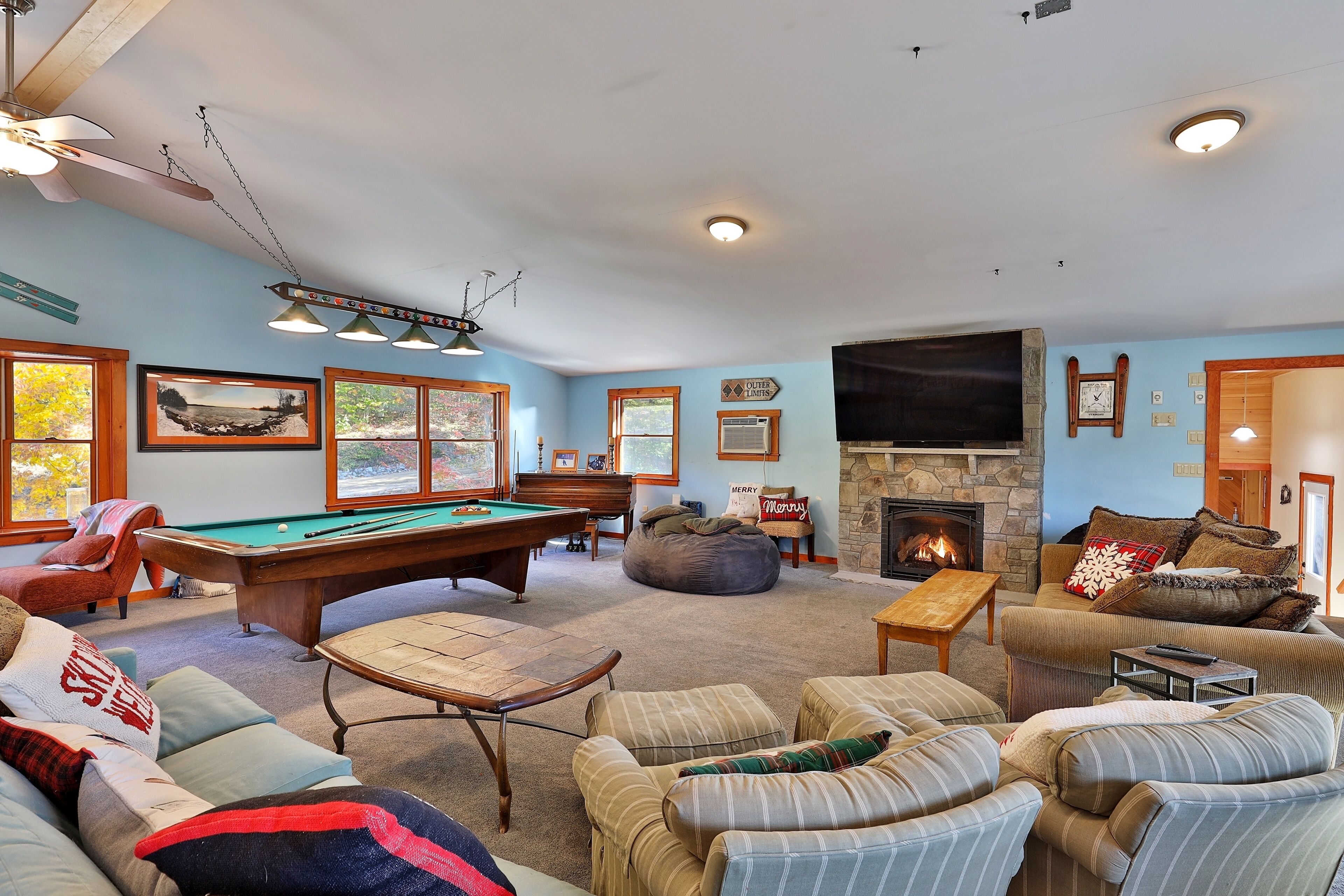 A cozy living room with a pool table, comfortable seating, a fireplace, and a television.