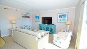A living room with a sofa, a television, a cabinet, and two lamps.