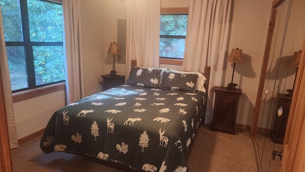 A bedroom with a bed, two bedside tables, a window, and curtains.