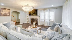 A living room with a fireplace, a chandelier, and a staircase. - Silver Springs Home: Walk to Downtown! (Silver Spring)