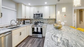 A modern kitchen with white cabinets, stainless steel appliances, a marble countertop, and pendant lighting. - Silver Springs Home: Walk to Downtown! (Silver Spring)