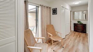 A room with two wicker chairs, a wooden floor, a sliding glass door, and a mirror on the wall.
