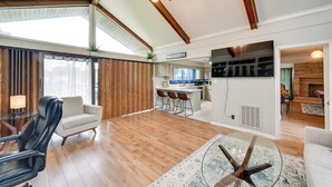 A spacious living area with a wooden floor, a ceiling fan, a glass coffee table, and a sofa.