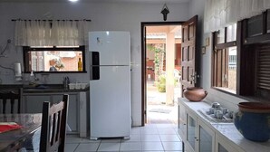 Una cocina compacta con refrigerador, una mesa de comedor y ventana con vista a un jardín.