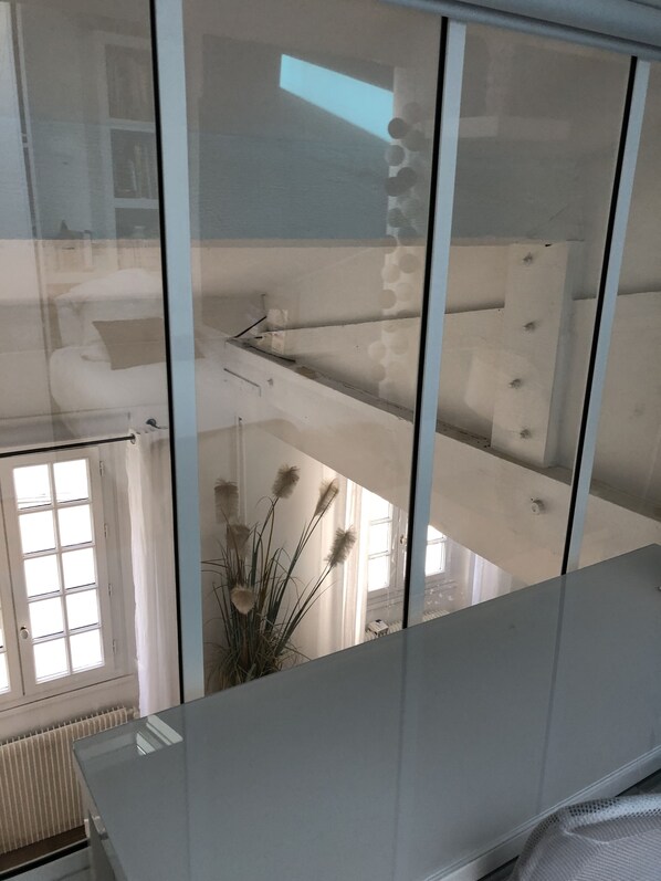 A room with a glass partition, a radiator, and a window with blinds.