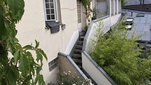 A building with a white facade, a window with a towel hanging, and a staircase leading to an upper level.
