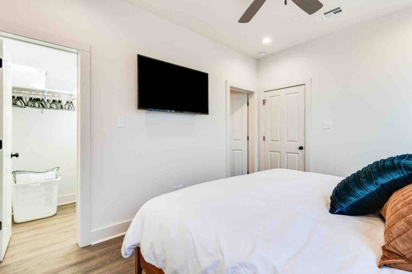 Une chambre à coucher avec un lit, un téléviseur fixé au mur, une armoire et une porte.