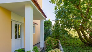 A building with a white door and a small window, surrounded by lush greenery and a garden. - 2 bedroom lovely apartment in Baska (Baska)