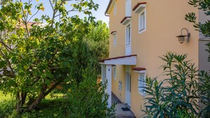 A two-story building with a yellow facade, a red roof, and a small balcony. - 2 bedroom lovely apartment in Baska (Baska)