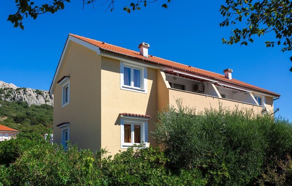 Un bâtiment à deux étages, avec un toit recouvert de tuiles rouges, des murs de couleur beige et de nombreuses fenêtres.